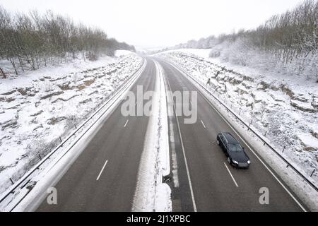 Una vista della A419 / A417 by pass con veicoli che viaggiano molto lentamente nella pericolosa condizioni stradali, nella foto dopo un pesante nevicata invernale la strada che teste attraverso il cuore di Cotswolds nel Regno Unito è a malapena praticabile in questi unusally cattive condizioni per viaggiare. Foto Stock