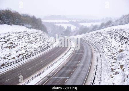 Una vista della A419 / A417 by pass con veicoli che viaggiano molto lentamente nella pericolosa condizioni stradali, nella foto dopo un pesante nevicata invernale la strada che teste attraverso il cuore di Cotswolds nel Regno Unito è a malapena praticabile in questi unusally cattive condizioni per viaggiare. Foto Stock