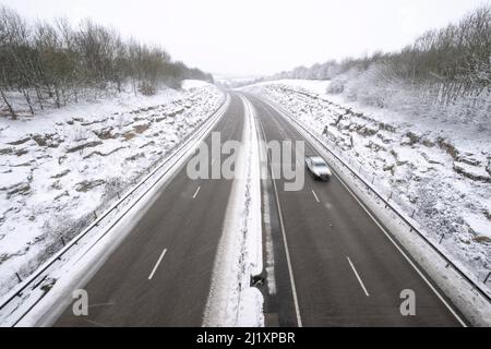 Una vista della A419 / A417 by pass con veicoli che viaggiano molto lentamente nella pericolosa condizioni stradali, nella foto dopo un pesante nevicata invernale la strada che teste attraverso il cuore di Cotswolds nel Regno Unito è a malapena praticabile in questi unusally cattive condizioni per viaggiare. Foto Stock