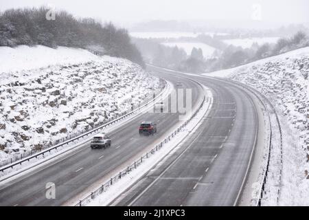 Una vista della A419 / A417 by pass con veicoli che viaggiano molto lentamente nella pericolosa condizioni stradali, nella foto dopo un pesante nevicata invernale la strada che teste attraverso il cuore di Cotswolds nel Regno Unito è a malapena praticabile in questi unusally cattive condizioni per viaggiare. Foto Stock