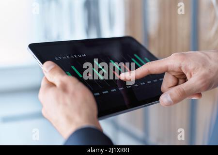 uomo d'affari che utilizza un tablet digitale per visualizzare i tassi di cambio della criptovaluta. Foto Stock