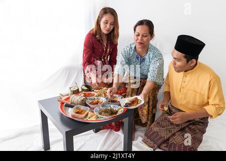 La famiglia Malay celebra la fine del Ramadan, il mese santo islamico, vestito con un abito tradizionale colorato, gustando una varietà di cucine tradizionali Foto Stock