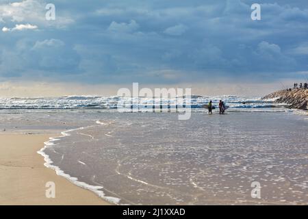 Due surfisti stanno camminando lungo la riva del mare. Foto Stock