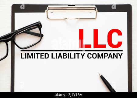 LLC Limited Liability Company - scrittura a mano su carta con tazza di caffè e penna, acronimo business concept. Foto Stock