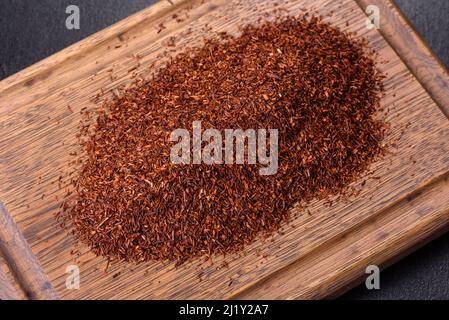 Tè Rooibos in una ciotola bianca su sfondo nero. Disposizione piatta, vista dall'alto, spazio di copia Foto Stock