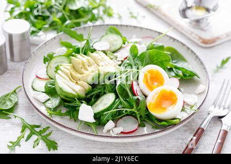 Avocado e uova sode insalata di verdure fresche con ravanello, cetrioli, spinaci, rucola e formaggio caserario Foto Stock