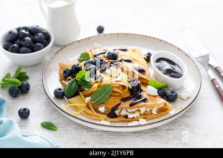 Crepes. Pancake sottili ripieni di formaggio caserario e mirtilli freschi Foto Stock