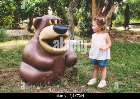 Cute giovane bianca ragazza caucasica mettendo una bottiglia di plastica non degradabile in un cestino di riciclaggio può Foto Stock