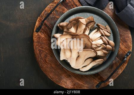 Funghi di ostrica freschi. Stira una vecchia ciotola di deliziosi funghi ostrica biologici su un vecchio sfondo di legno, vista dall'alto con spazio per il testo. Foto Stock