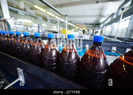 Bottiglie di birra in plastica su un nastro trasportatore sullo sfondo di una fabbrica di birra Foto Stock