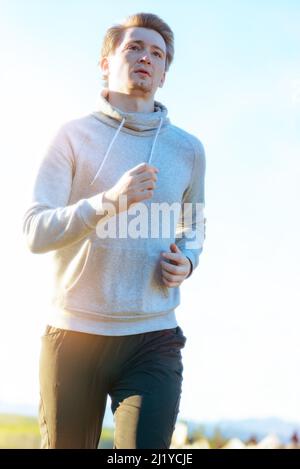 L'uomo che fa jogging nella natura rurale durante la splendida giornata estiva. Sport fitness modello caucasico etnia formazione all'aperto. Foto Stock