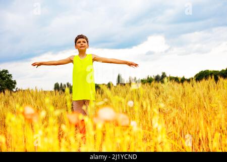 Ragazzo stare in piedi nel campo di grano con le mani sollevate Foto Stock