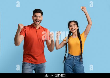 Grande successo. Coppia euforica del Medio Oriente che alza i Fists ed esclamando con eccitamento Foto Stock