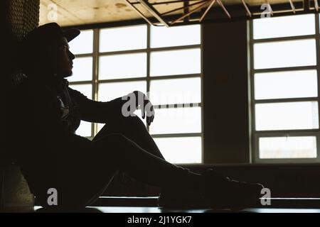 Ritratto di un giovane atleta maschile in un cappellino da baseball e felpa in un interno palestra Foto Stock
