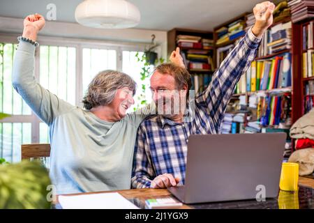 Coppia anziana entusiasta sorpreso da buone notizie, enorme offerta di vendita sul sito web, coppia anziana overjoyed usando il laptop, sentendosi felice e vincendo Foto Stock