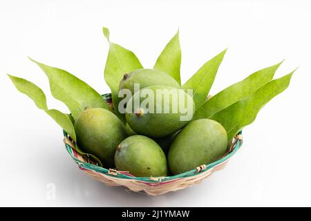 Primo piano di freschi manghi verdi crudi chiamato anche Kacha Khatta AAM con foglie in cesto di bambù. Isolato su sfondo bianco con spazio di copia Foto Stock