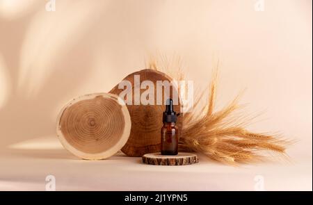 Olio organico di cereali segale e frumento in bottiglia con contagocce in piedi su un podio di legno su sfondo beige. Foto Stock