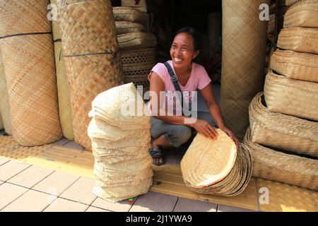 Un venditore locale che vende cestini e cappelli di rattan al mercato di Sukawati a Sukawati, Gianyar, Bali. Foto Stock