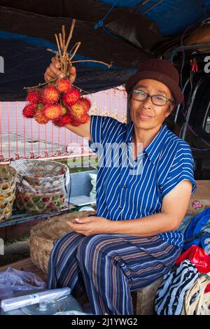 Un venditore locale che vende rambutan al mercato di Sukawati a Sukawati, Gianyar, Bali. Foto Stock