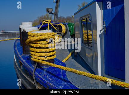 Frontside di una chiatta in blu brillante con bollards e corda gialla (e riflessi in una finestra) sul fiume meno, in Germania Foto Stock