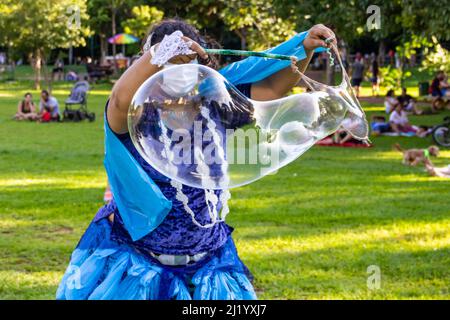 Goiânia, Goias, Brasile – 01 marzo 2022: Una ragazza che soffia enormi bolle di sapone. Foto scattata durante il Carnevale di strada in un parco pubblico della città. Foto Stock