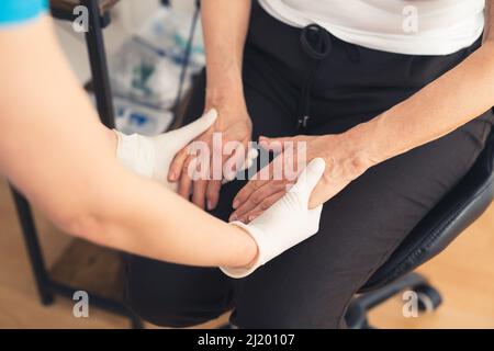 Primo piano dell'infermiere e della donna anziana caucasica che tiene le mani. Assistenza sanitaria. Foto di alta qualità Foto Stock