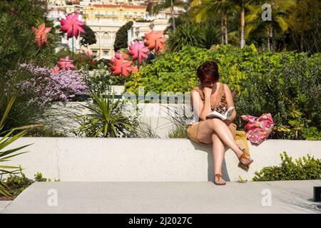 Monte Carlo, Monaco. 28th Mar 2022. Una donna legge un libro in Piazza Casino, Monte-Carlo in una giornata calda e soleggiata. Credit: SOPA Images Limited/Alamy Live News Foto Stock