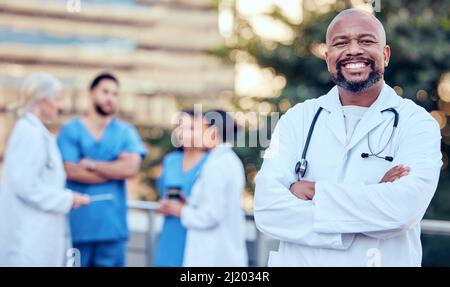 Theres niente che cant fix con un sorriso. Colpo di un medico maschio maturo in piedi con le braccia incrociate in città. Foto Stock