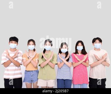 Giovani che indossano maschere facciali durante la pandemia di covid-19. Gruppo di adolescenti con gesti di negazione Foto Stock