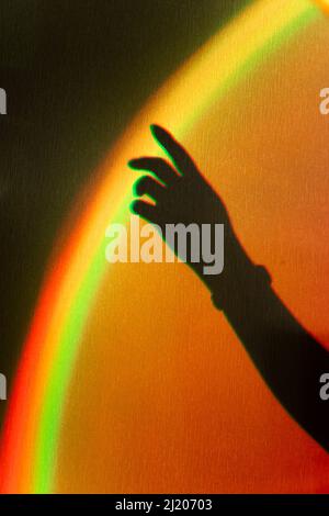 Ombra della mano del woman. Riflesso arcobaleno del fascio solare sulla parete. La mano tocca l'arcobaleno. Concetto di sogni e speranze. Foto Stock