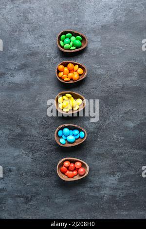 Metà delle uova di Pasqua con caramelle diverse su sfondo scuro Foto Stock