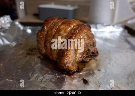 Primo piano, focalizzazione selettiva su un succoso arrosto di chashu di maiale poggiato su foglio di stagno dopo essere stato cotto Foto Stock