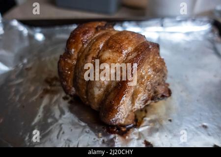 Primo piano, focalizzazione selettiva su un succoso arrosto di chashu di maiale poggiato su foglio di stagno dopo essere stato cotto Foto Stock