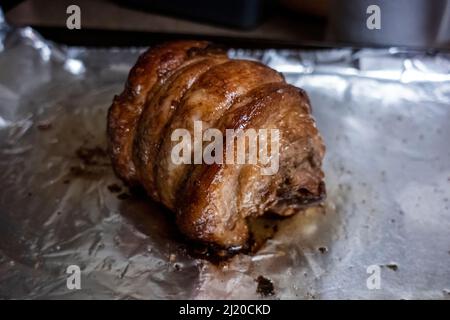 Primo piano, focalizzazione selettiva su un succoso arrosto di chashu di maiale poggiato su foglio di stagno dopo essere stato cotto Foto Stock