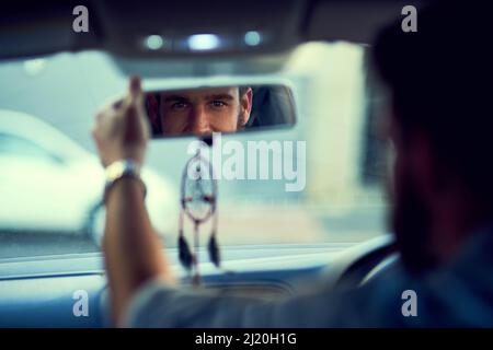 Sono pronto per la giornata. Scatto all'indietro di un uomo irriconoscibile che guida in auto guardando nello specchietto retrovisore. Foto Stock