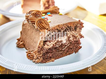 Pezzo di torta al cioccolato con decorazioni su un piatto di carta con profondità di campo poco profonda Foto Stock