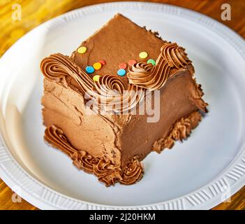 Pezzo di torta al cioccolato con decorazioni su un piatto di carta con profondità di campo poco profonda Foto Stock