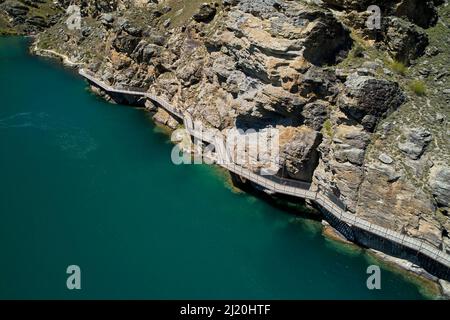 Ciclisti sul ponte a sbalzo sul sentiero ciclabile del lago Dunstan e sul lago Dunstan, vicino a Cromwell, Otago centrale, Isola del Sud, Nuova Zelanda - antenna drone Foto Stock