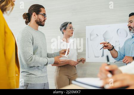Team di progettisti creativi che hanno una discussione mentre lavorano con i modelli e i disegni di turbine eoliche 3D. Gruppo di imprenditori innovativi che progettano un r Foto Stock