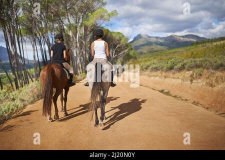 Andare per un giro. Vista posteriore di due donne a cavallo - percorso a cavallo. Foto Stock