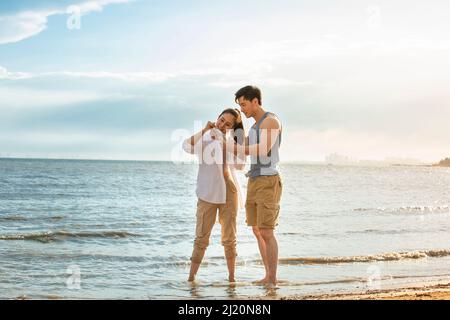 Giovane coppia che scopre la bottiglia di drift sulla spiaggia estiva - foto di scorta Foto Stock