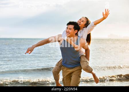Marito che porta la moglie su una spiaggia estiva - foto di scorta Foto Stock