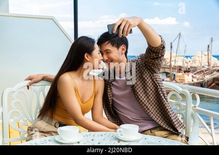 Le coppie sono felici di fare selfie in un caffè sul mare - foto di scorta Foto Stock