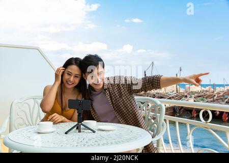 Giovane coppia video-chatting sui loro telefoni cellulari al ristorante Ocean View - foto di scorta Foto Stock