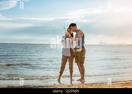 Giovane coppia che scopre la bottiglia di drift sulla spiaggia estiva - foto di scorta Foto Stock