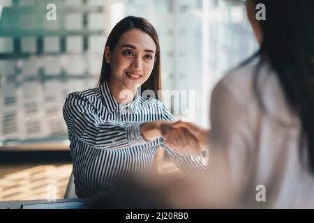 I giovani uomini d'affari asiatici scuotono le mani in ufficio. Conclusione della riunione riuscita. Foto Stock