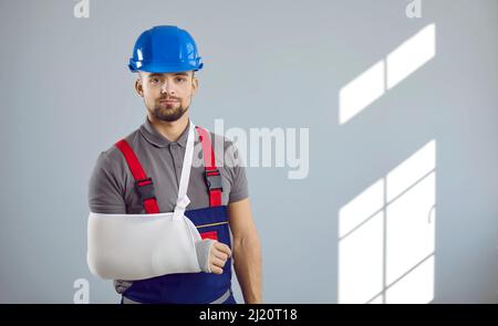 Ritratto di giovane costruttore che ha rotto il suo braccio in un incidente di lavoro in cantiere Foto Stock