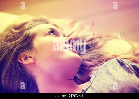 Il quadro della nostalgia. Una giovane ragazza attraente che si trova sul suo divano a casa. Foto Stock