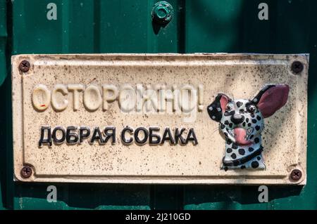 Kiev, Ucraina - 3 luglio 2021: Un cartello appluso sulla recinzione di fronte ad una casa suburbana. Il cartello recita 'attenzione! Cane gentile. C'è un disegno di un cane Foto Stock