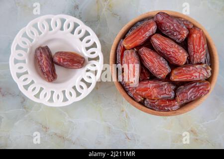 Date frutta in due ciotole su sfondo marmo colorato, vista dall'alto Foto Stock